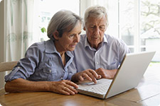 Mature couple interacting with laptop computer.